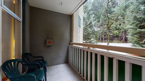 Ein Balkon mit Blick auf einen Wald, ein Stuhl und ein Thermostat.