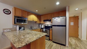 Una cocina con encimeras de granito, gabinetes de madera y electrodomésticos de acero inoxidable, además de un microondas integrado.