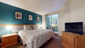 Un dormitorio con cama, televisor, mesita de noche y cómoda.