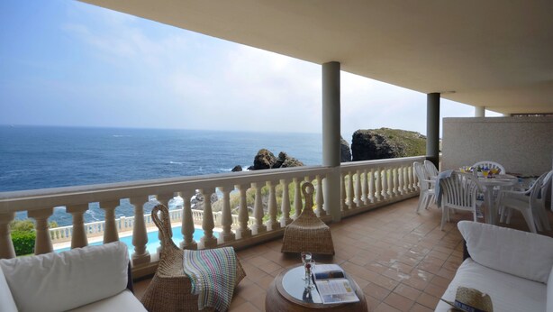A balcony with a view of the sea, white outdoor furniture, and a table with a menu. - Holiday rental apartment with swimming pool in Begur, Aiguafreda (Begur)