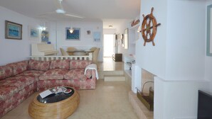 A living room with a sofa, a coffee table, a ceiling fan, and a wall-mounted ship's wheel. - Holiday rental apartment with swimming pool in Begur, Aiguafreda (Begur)