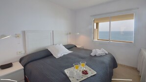 A hotel room with a bed, a tray with breakfast, and a window with a view of the sea. - Holiday rental apartment with swimming pool in Begur, Aiguafreda (Begur)