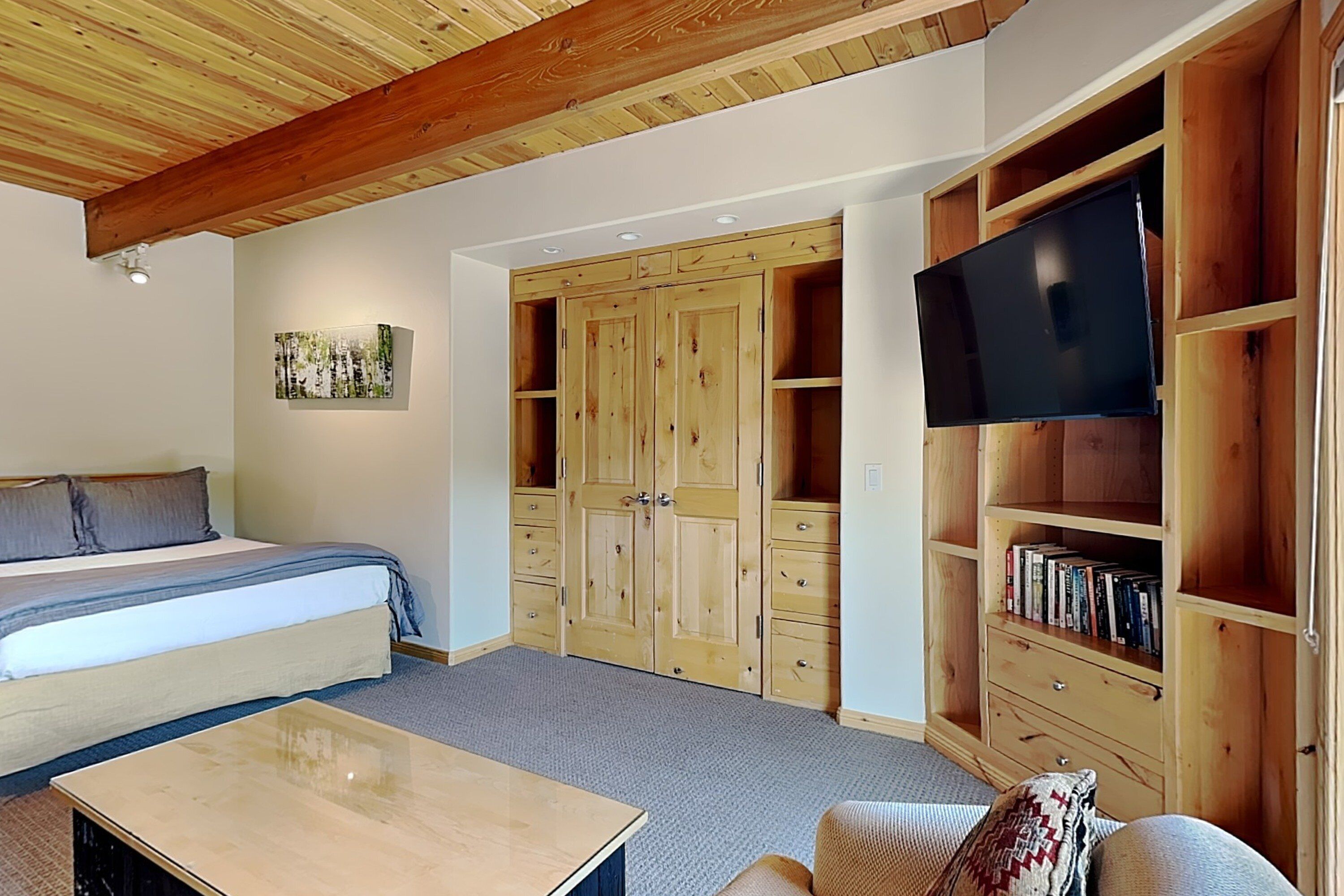 Une chambre à coucher avec un lit, une armoire en bois, un téléviseur et une bibliothèque.