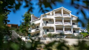 Un immeuble résidentiel à plusieurs étages, doté de balcons, d’un escalier et surplombant un ciel bleu dégagé.