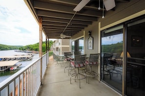 A covered balcony with outdoor seating, a view of the water, and a clock on the wall.