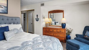 Une chambre à coucher avec un lit, une commode, une chaise et un ventilateur de plafond.