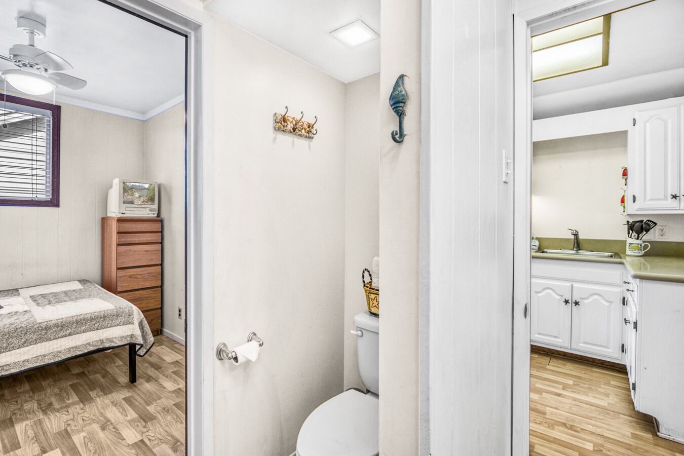 A compact bedroom with a bed, a wooden dresser, a toilet, and a shower area.