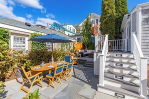 En terrasse med et træbord og stole, en blå parasol og en trappe til en træterrasse.