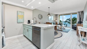 A modern kitchen with a central island, a dining area with a view, and a living space with a balcony. - Beach Condo/ High-End Finishes/ Island Beach Resort/No Cleaning Fee/ Condo 403 (Jensen Beach)