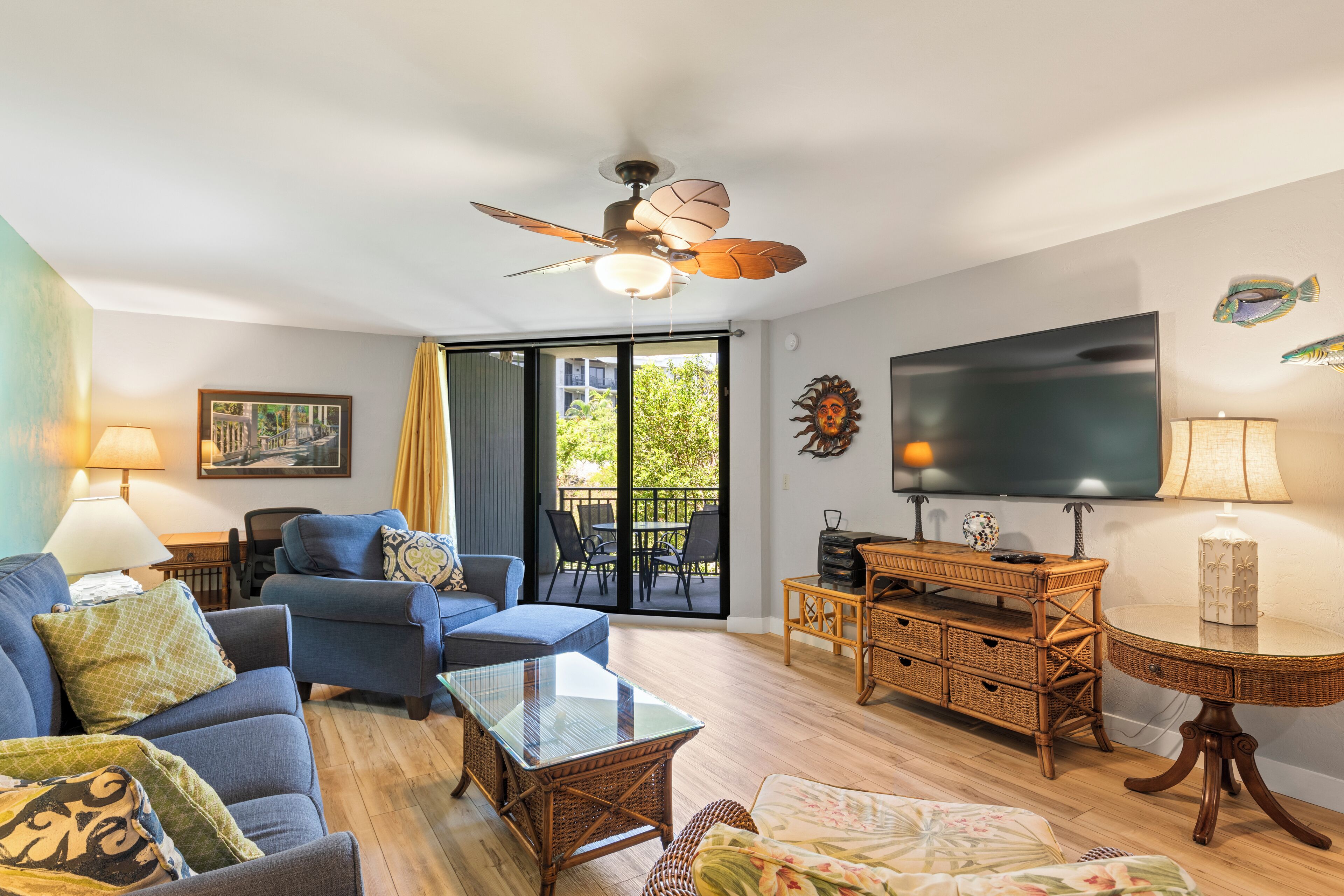 Un salon comprenant un canapé, un fauteuil, une table basse, un téléviseur et un ventilateur de plafond.