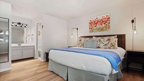 Ein Schlafzimmer mit Bett, Nachttischen, einem Waschtisch und einer Toilette.