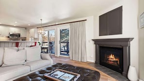 A modern living room with a fireplace, a sofa, a dining area, and a kitchen. - Snowmass - Woodbridge Condos 27A (Snowmass Village)