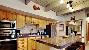 Une cuisine moderne avec des meubles en bois, des appareils en acier inoxydable et un plan de travail en granit.