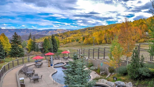 Un espace patio avec des sièges d’extérieur, une petite piscine et une vue sur le feuillage automnal et les montagnes.