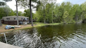 A lakeside property with a dock, a house, and a grassy area with picnic tables.