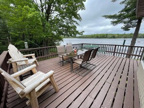 A wooden deck with Adirondack chairs, a table, and a view of a lake. - Spectacular Fall Color View! Dock,Swimming, great Fishing, boat, canoe, kayaks! (Wetmore)