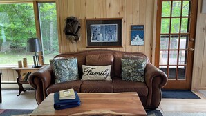 A cozy living room with a brown leather couch, a wooden coffee table, and a framed picture on the wall.