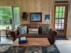 A cozy living room with a brown leather couch, a wooden coffee table, and a framed picture on the wall.