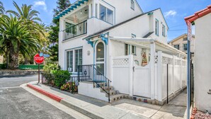 Ein zweistöckiges Haus mit Balkon und weißem Zaun, im Vordergrund ein Stoppschild.