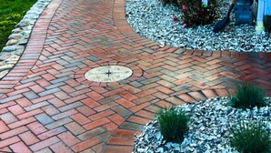A curved brick pathway leading to a building with a blue exterior.