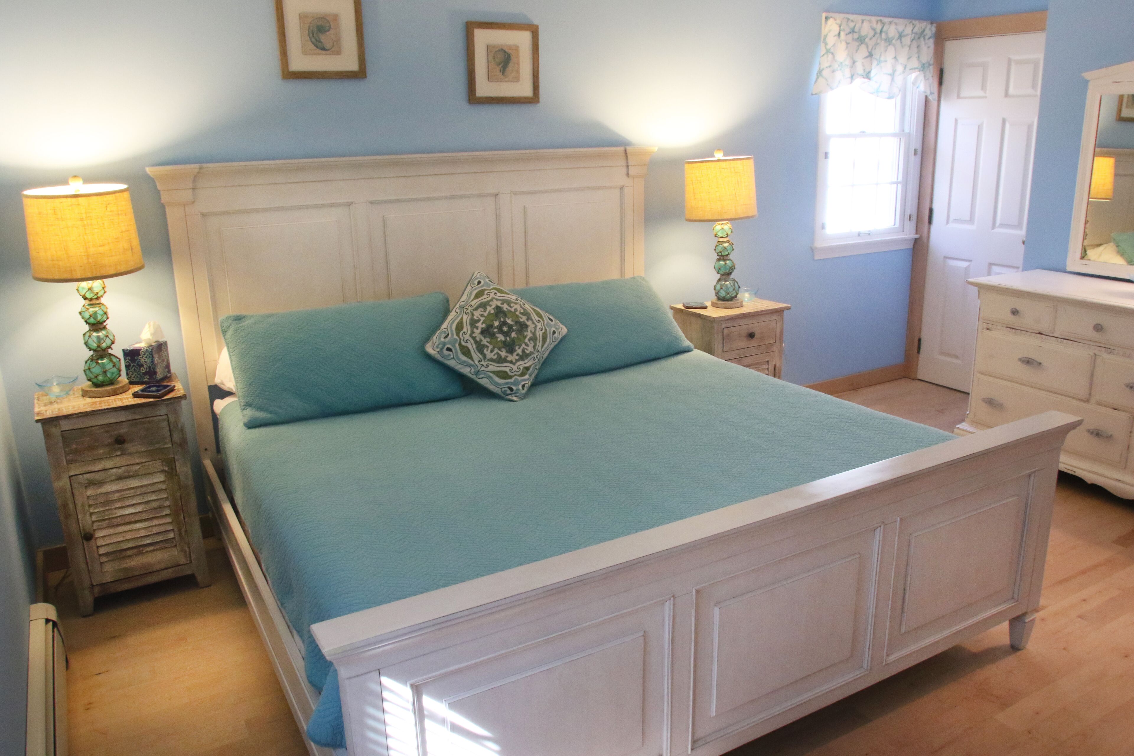 Una camera da letto con un letto, due comodini, una cassettiera e una finestra con tende.