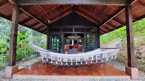 A wooden structure with a hammock, a sofa, and a dining area under a covered roof. - Stylish Open Living, Garden Bathroom & Pool for Honeymooner and Nature Lovers (Uvita)