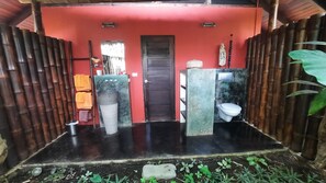 Une salle de bain avec un mur rouge, une porte en bois, un lavabo et des toilettes.