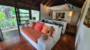 A modern living area with a white sofa, red and orange cushions, a woven lamp, and a stone decoration. - Stylish Open Living, Garden Bathroom & Pool for Honeymooner and Nature Lovers (Uvita)
