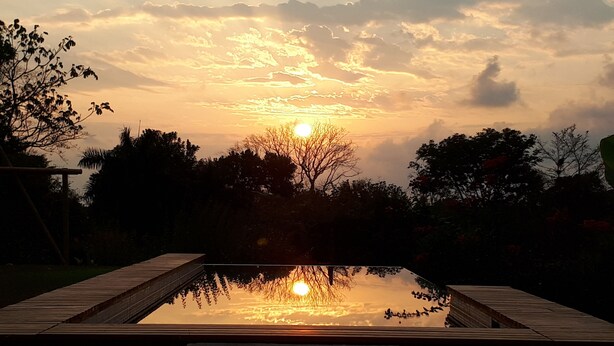 A sunset over a body of water with a wooden deck in the foreground. - Stylish Open Living, Garden Bathroom & Pool for Honeymooner and Nature Lovers (Uvita)