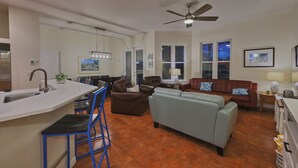 A modern kitchen with a bar area, a dining set, a living room with a sofa and a coffee table, and a ceiling fan. - Canal front pool home on the north end of Anna Maria Island (Anna Maria)