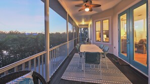 A covered porch with a table and chairs, a ceiling fan, and a view of the outdoors. - Canal front pool home on the north end of Anna Maria Island (Anna Maria)