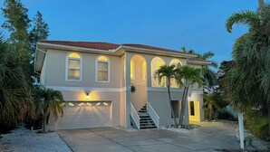 A two-story house with a garage, a staircase, and a well-lit entrance. - Canal front pool home on the north end of Anna Maria Island (Anna Maria)