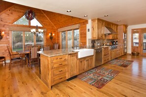 A spacious kitchen with wooden cabinets, a large island, and a dining area with chairs.