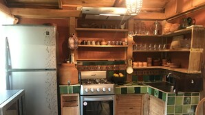 A compact kitchen with a refrigerator, stove, and wooden cabinets.