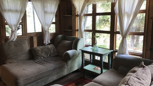 A cozy room with a sofa, a small table, and a window with curtains.