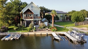 A house with a large deck, a covered porch, and a dock with kayaks and a boat. - Monthly rental getaway on lake LBJ (Kingsland)