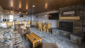 Una sala de estar acogedora con chimenea de piedra, muebles de madera y una zona de cocina con electrodomésticos modernos.