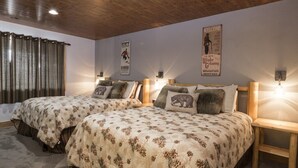 Habitación con dos camas, cada una con ropa de cama floral y un cojín de oso. Hay lámparas de pared, un cartel en la pared y una ventana con cortinas.