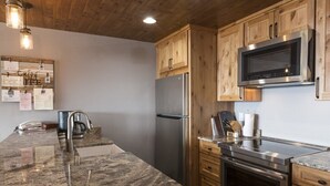 Una cocina con encimeras de granito, electrodomésticos de acero inoxidable, armarios de madera y un microondas integrado.