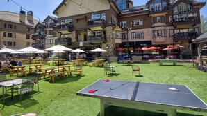 Un espace extérieur aménagé avec des tables et des chaises, une table de ping-pong et un bâtiment doté de nombreux balcons et fenêtres.