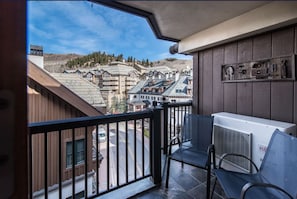A balcony with a view of a town, a window, and an air conditioning unit.
