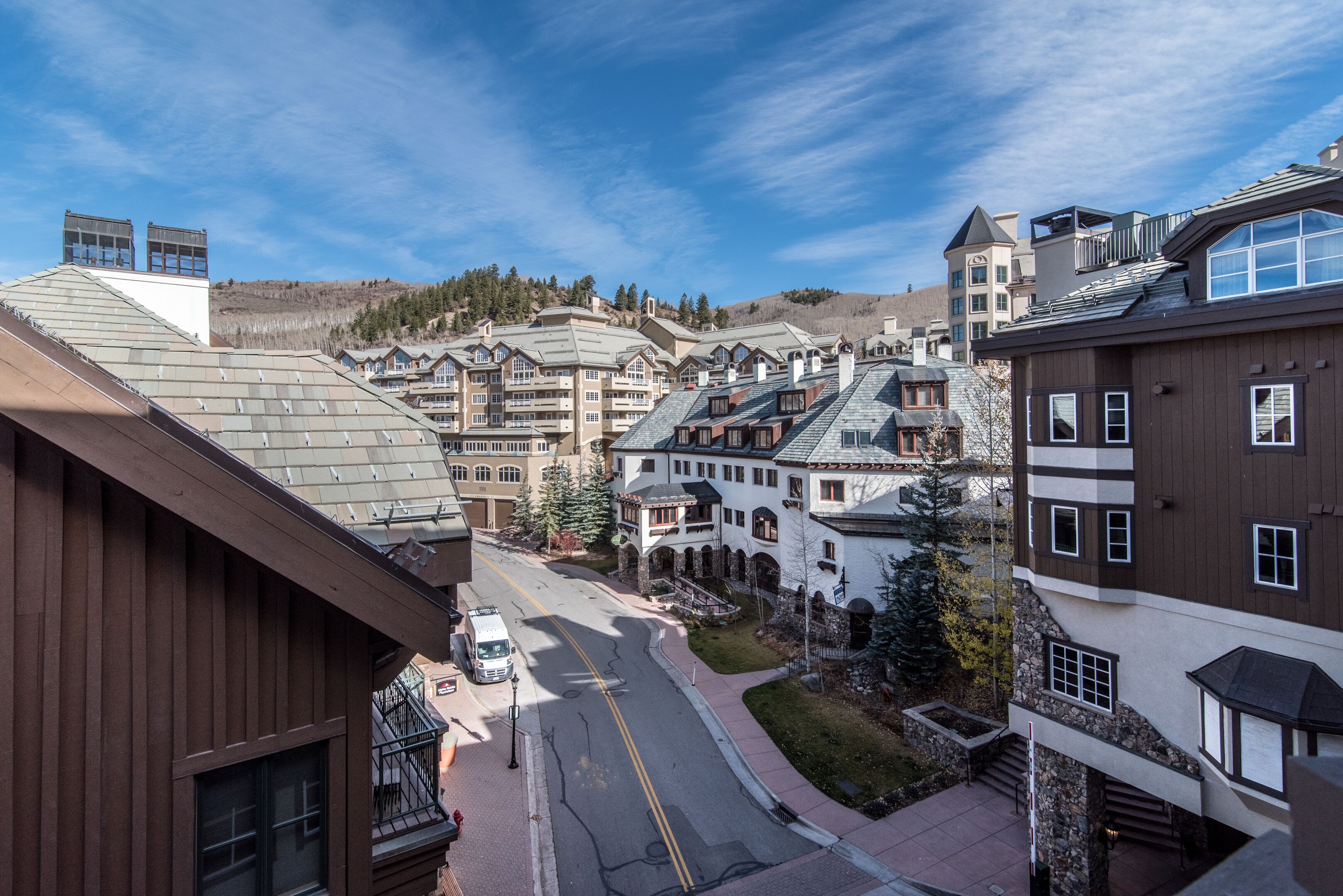 A hotel with multiple buildings, a street with a vehicle, and a clear sky.
