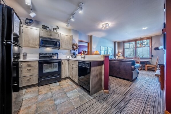A modern kitchen with built-in appliances, a dining area with a table and chairs, and a large window providing natural light.