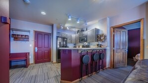 A compact kitchen with a central island, a red bench, and a wooden door. - Ski in/Ski out condo w/great views. Overlooking the slopes. Access to hot tub (Winter Park)