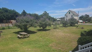 A grassy yard with a picnic table, trees, and a house in the background.