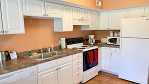 A kitchen with white cabinets, a stove, a sink, and a refrigerator.