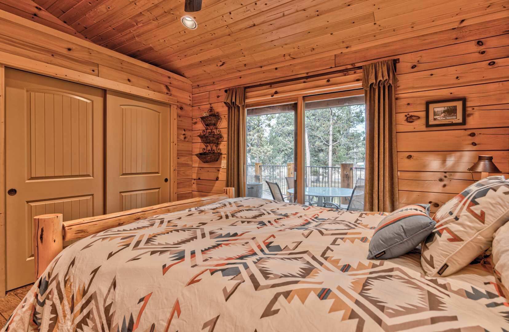 A wooden cabin bedroom with a bed, a window, and a balcony.