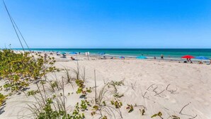A beach with clear skies, sandy shore, and beach umbrellas.