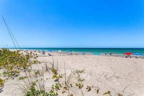 Ein Strand mit blauem Himmel, sandigem Ufer und Strandliegen.