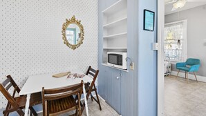 Een eetgedeelte met een witte tafel, houten stoelen, een decoratieve spiegel en een blauwe wand met planken.